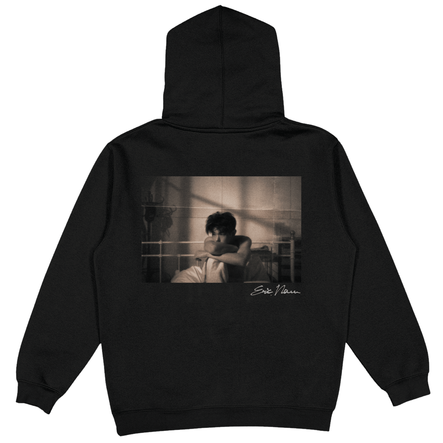 A black pullover hoodie shown from the back, featuring a large rectangular sepia-toned graphic print of a Eric Nam. A small white Eric Nam script signature is printed below the graphic.